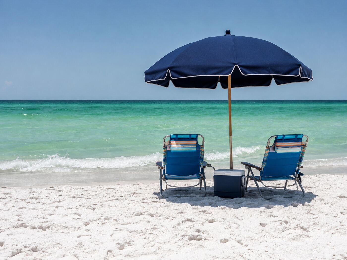 Beach chairs and umbrella set up on white PCB sand